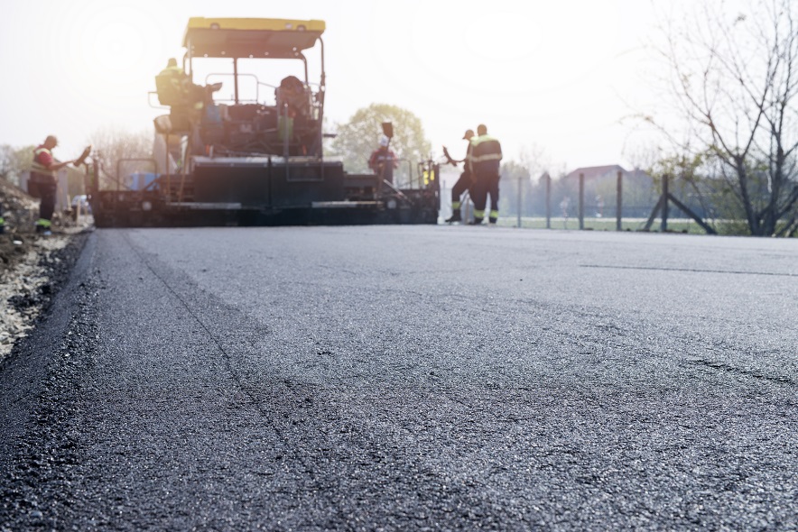 pracownicy ukladaja nowa warstwe asfaltu na jezdni